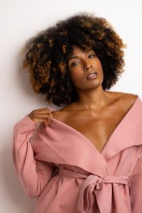 Stylish portrait of a woman wearing a pink off-shoulder wrap, showcasing natural beauty.